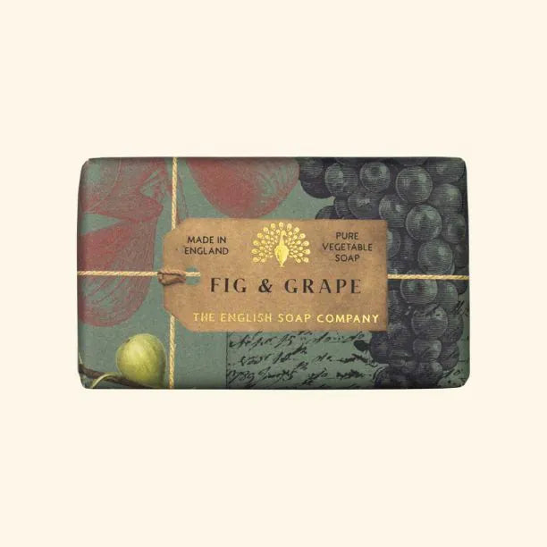 A bar of eco-friendly Anniversary Fig and Grape Soap by The English Soap Company, wrapped in decorative fruit-themed paper with a brown band indicating it is pure vegetable soap.