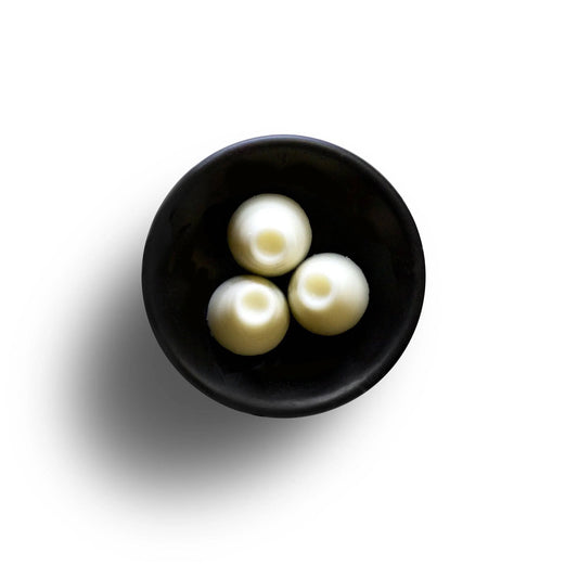 A black bowl cradles three round, vegan mochi balls, set against a pristine white background.
