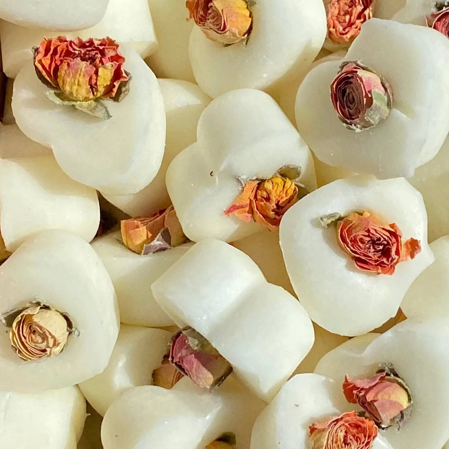 Heart-shaped white sweets topped with dried rosebuds, inspired by the English Rose Soya Wax Melt, offer a vegan-friendly treat reminiscent of luxury home fragrance.