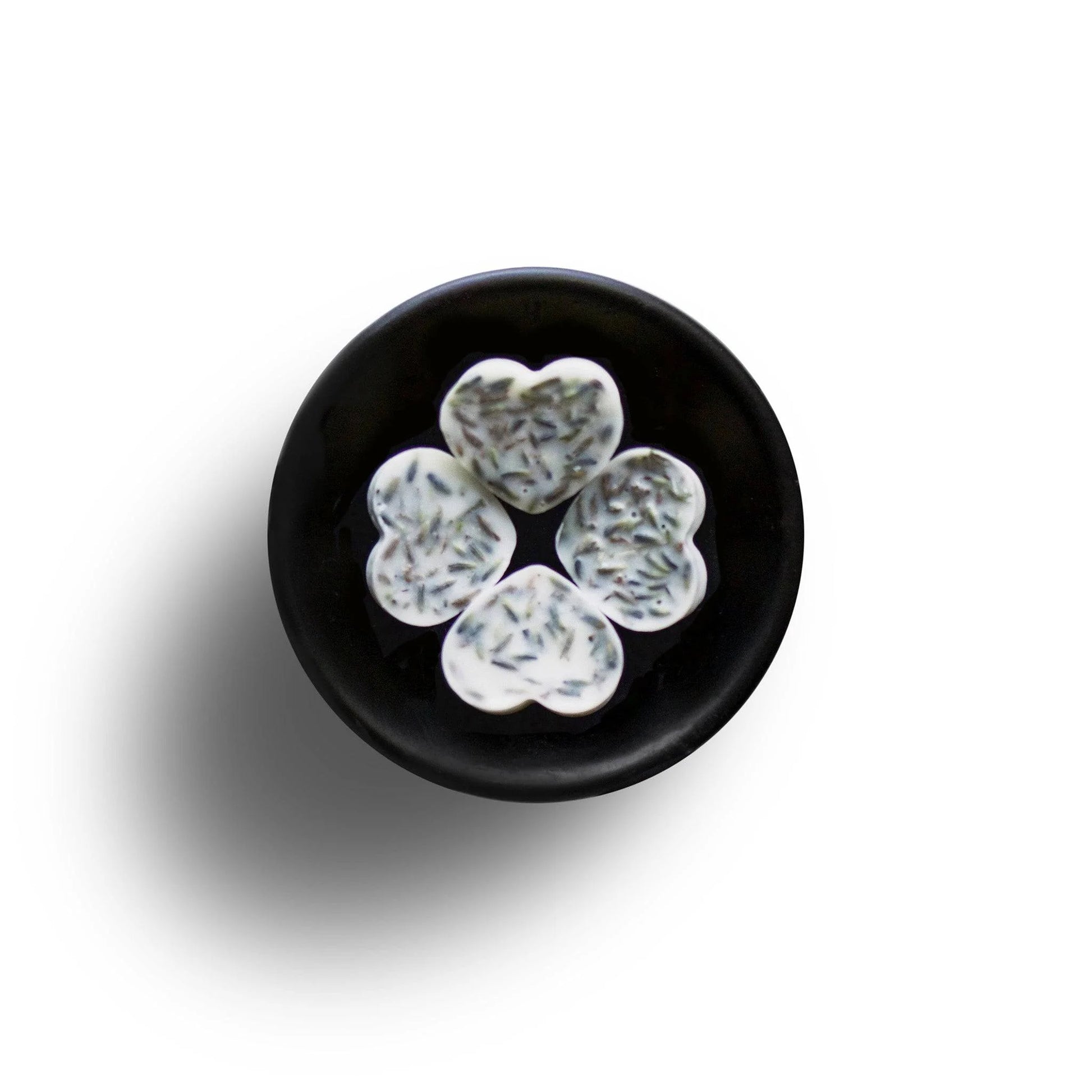 Five heart-shaped biscuits with sprinkled toppings arranged in a circle on a black plate against a white background, creating an inviting scene reminiscent of a Lavender Soya Wax Melt infused with essential oils.