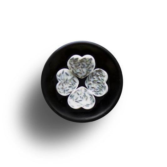 Five heart-shaped biscuits with sprinkled toppings arranged in a circle on a black plate against a white background, creating an inviting scene reminiscent of a Lavender Soya Wax Melt infused with essential oils.
