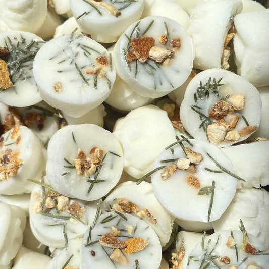 A close-up of eco-friendly wax melts, crafted from paraffin-free white wax and adorned with dried herbs and orange peel.