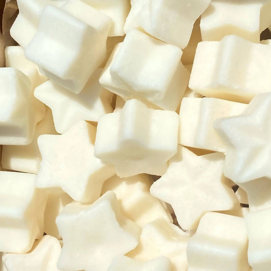 A collection of star-shaped and square-shaped white marshmallows, reminiscent of vegan wax melts, viewed from above and closely packed together.