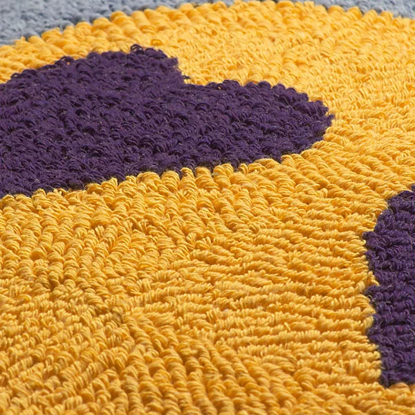 Close-up view of textured yellow fabric adorned with dark purple shapes, ideal for adding a splash of colour to your home décor—potentially part of a contemporary rug or polyester cushion.