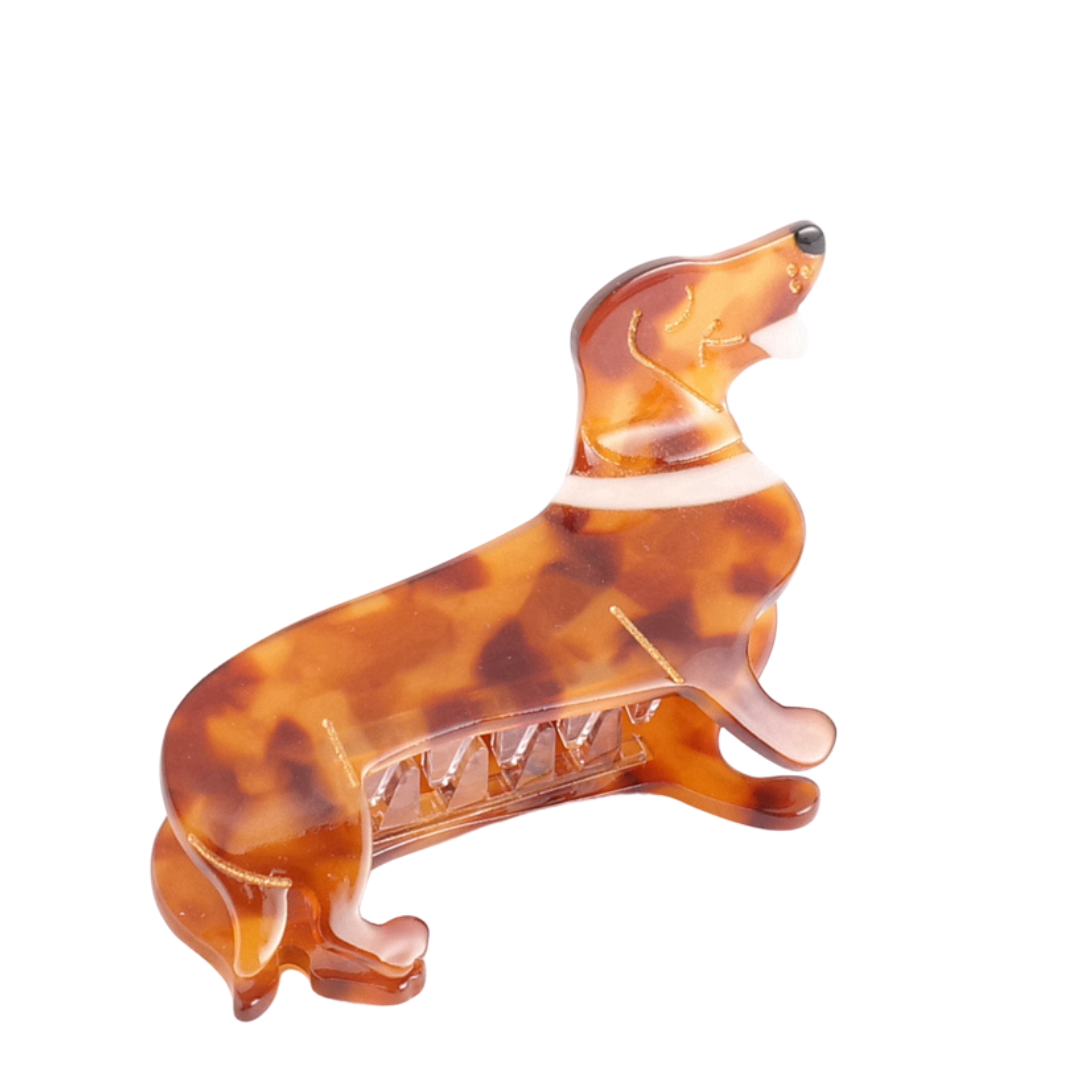 The Sausage Dog Hair Claw Clip is a delightful hair accessory, crafted from brown tortoiseshell-patterned acetate. It depicts a dachshund in profile with a visible spring mechanism, adding playful charm to your hairstyle.
