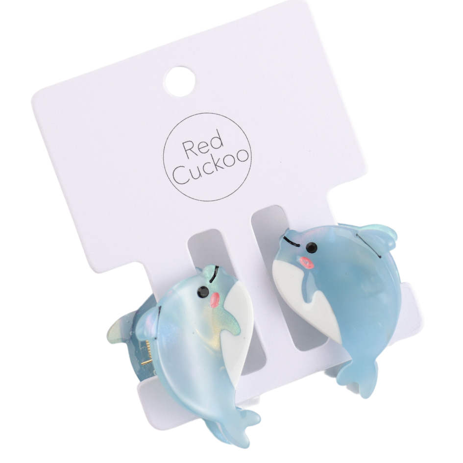 Two durable and stylish dolphin-shaped hair accessory clips in a soothing blue hue are placed on a white card labelled Red Cuckoo.