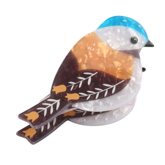 Illustrated bird-shaped brooch exuding elegance, featuring blue, brown, and orange tones with leaf patterns on its wings—perfectly complementing any stylish hairstyle.
