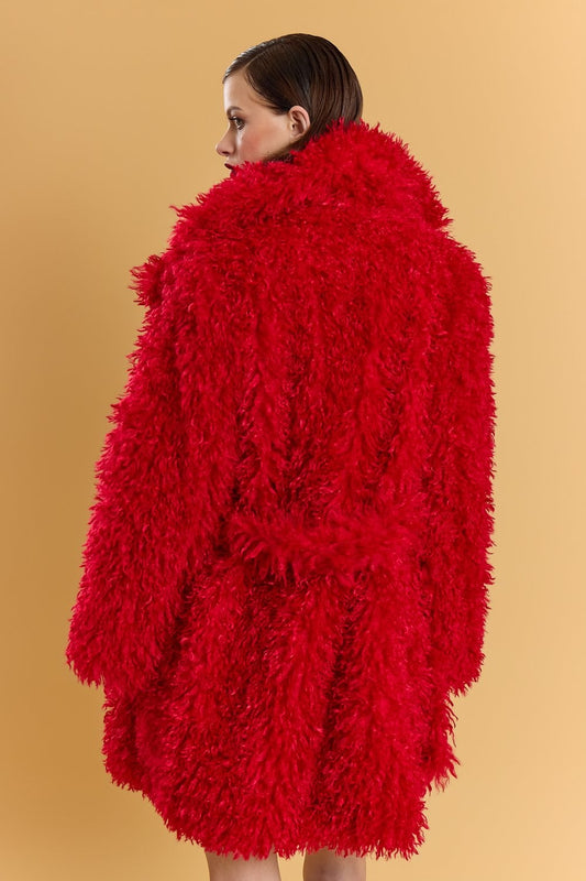 Individual wearing a vibrant red Bamboo Blend Faux Fur Coat, viewed from behind against a simple beige background.