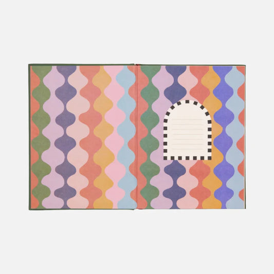 An open Orange Monkeys Journal hardback notebook featuring a colourful, wavy geometric pattern and a small lined label bordered by a black-and-white arch on the right page—an ideal stationery gift.