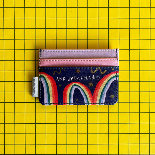 A multicoloured, pocket-sized cardholder with pink slots and AND UNDERFUNDED text, set on a yellow, grid-patterned background—a fun present for mates.
