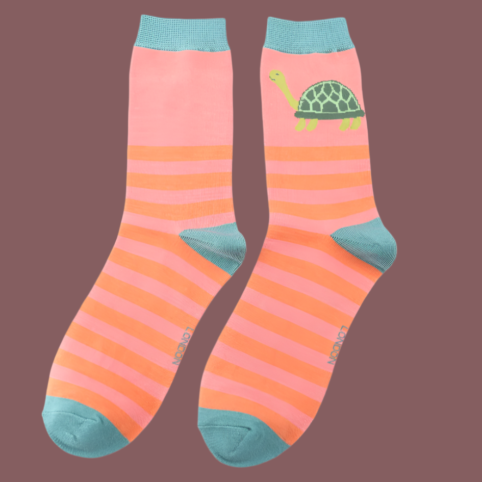 A pair of pink and orange striped socks with teal cuffs, heels, and toes, featuring an illustration of a green tortoise on one sock.