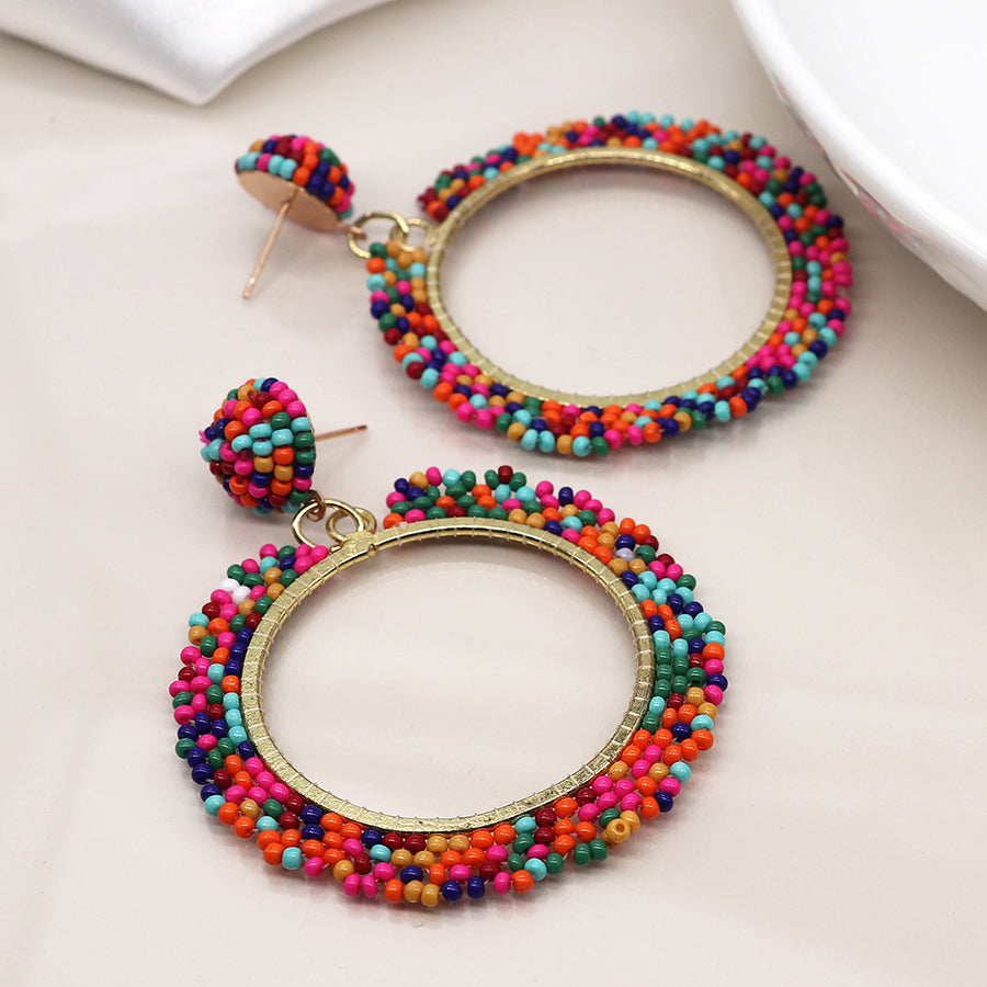 Colourful hoop drop earrings featuring vibrant mixed beads and small circular stud attachments, all elegantly complemented by faux gold plating on a light background.