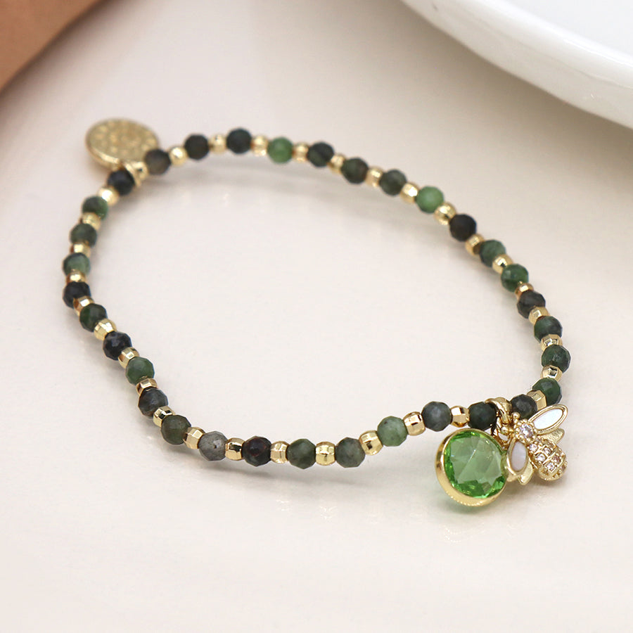 A Green & Gold Bracelet adorned with a faux gold-plated bee charm, shimmering with green and gold beads and a striking green gemstone pendant.