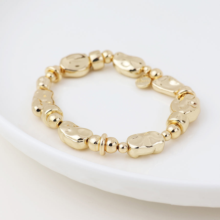 A mixed bead bracelet with irregularly shaped, polished links and small round beads, made from vegan-friendly materials and shown on a white dish.