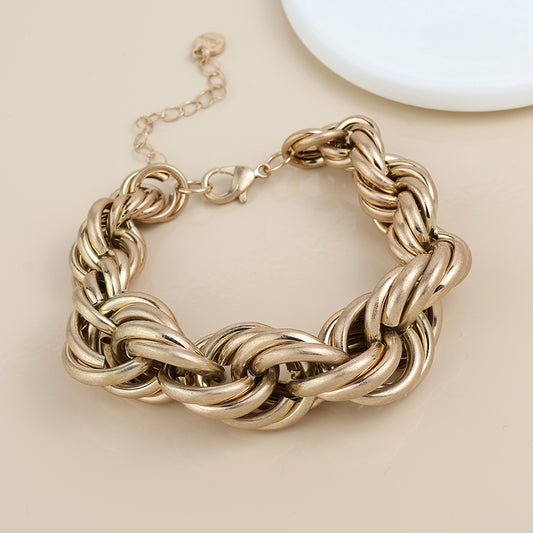 Gold chunky chain bracelet featuring large interlocking links, a lobster clasp, and adjustable extender, shown on a beige surface beside a white round dish—ideal statement jewellery for any outfit.