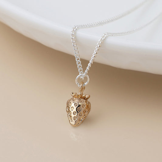 A silver chain strawberry necklace featuring a gold fruit jewellery pendant is shown against a neutral background.
