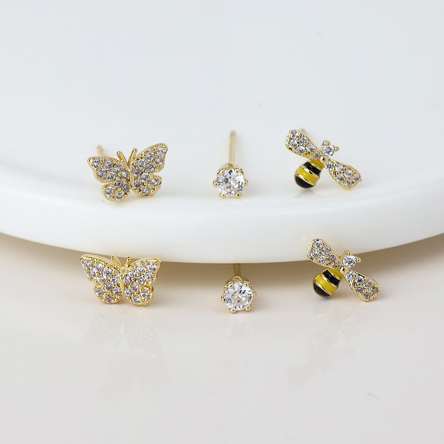 Gold butterfly earrings, bee earrings, and crystal stud designs are shown on a white surface.