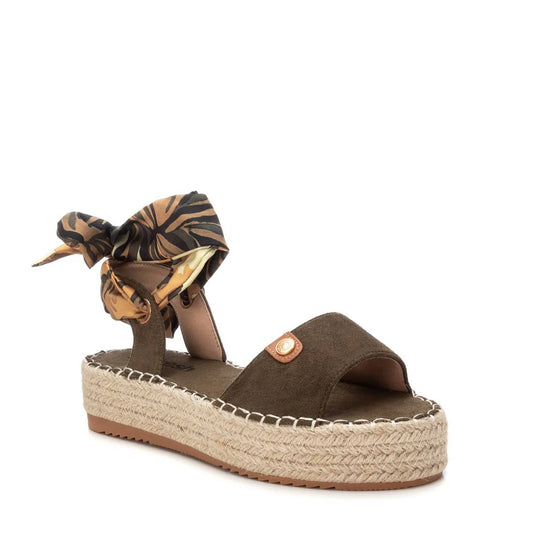 A brown suede S.Ant Khaki Sandal with an open toe, woven espadrille sole, and an ankle strap tied with a patterned fabric bow—perfect for lovers of luxury footwear.