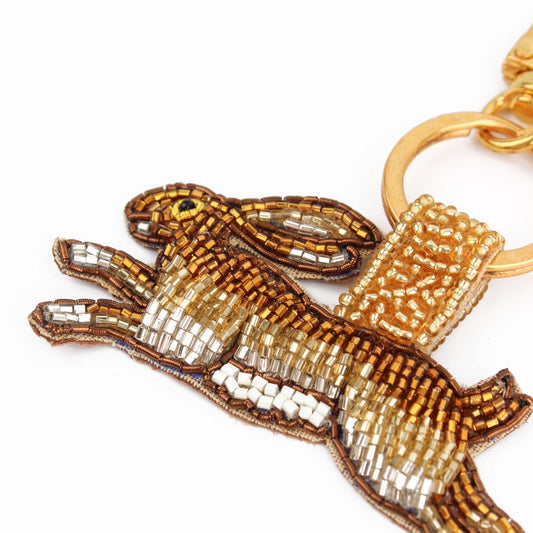 Introducing the Golden Hare Keyring, a delightful accessory for animal lovers featuring a beaded keychain in the shape of a leaping hare. Adorned with brown, gold, and white beads, it comes with a gold keyring for added elegance.