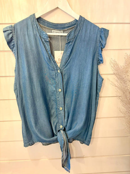 Sleeveless chambray button-up shirt featuring a front tie, made from eco-friendly vegan materials, shown on a white hanger against a light wooden background.