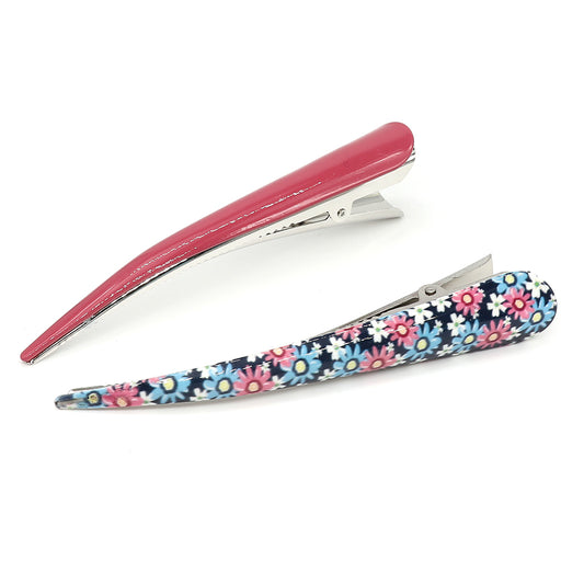 Two long hair clips are on display: a solid red one and the other from the Pink & Blue Floral Hair Clip Duo, adorned with an elegant floral pattern for the fashion connoisseur.