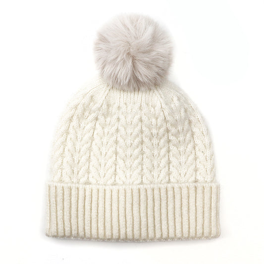 A cream knitted beanie crafted from recycled vegan yarn, featuring a turned-up brim and a large, fluffy pom-pom—a sustainable winter hat that’s both cosy and stylish.