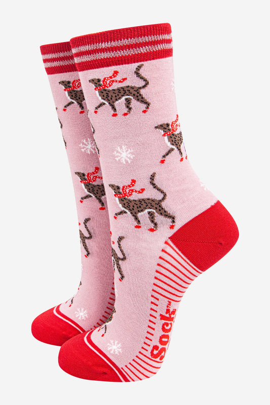 These cheerful socks showcase cheetahs in red scarves, white snowflakes, and striking pink and red details. The word "Sock" is printed near the sole for a playful finishing touch.