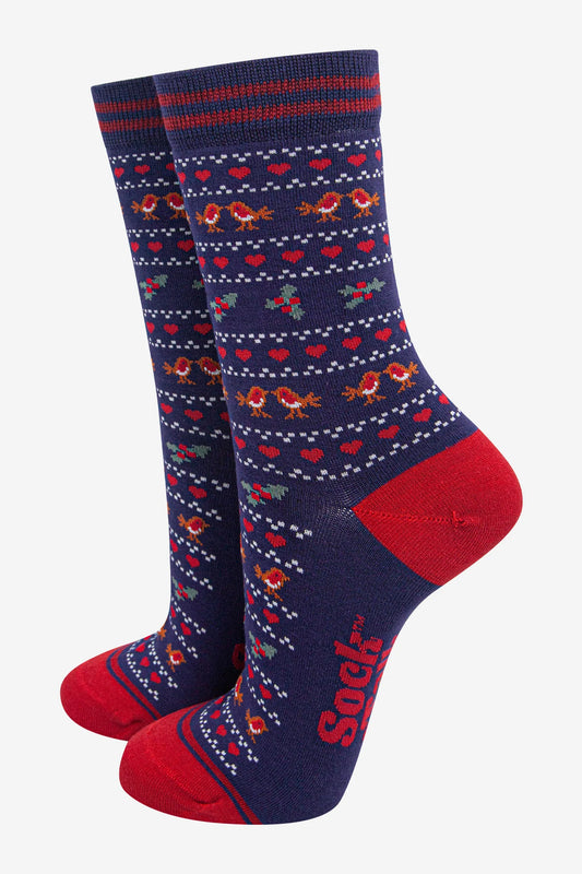 Pair of navy blue vegan-friendly socks with red toes, heels, and cuffs, adorned with a colourful pattern of small flowers and the word 'Sock' printed on the side.