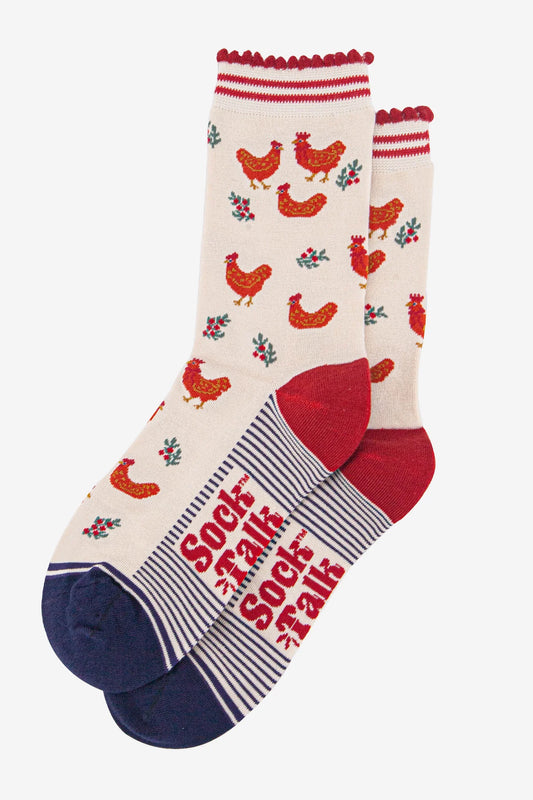A pair of cream-coloured vegan festive socks featuring red chickens and floral patterns, with red heels and toes, and 'Sock Talk' text on the soles.