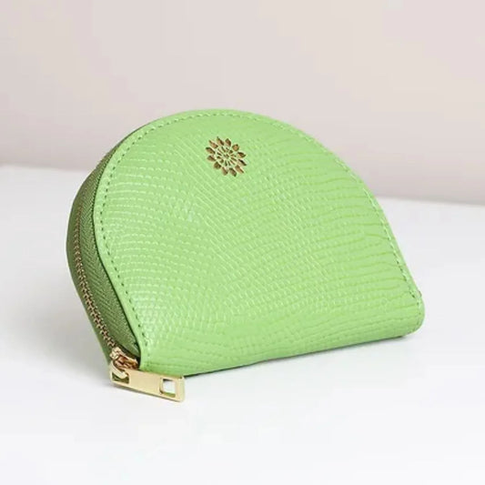 A small, green, half-moon coin purse made from vegan leather with a gold zip and gold emblem on the front, placed on a white surface.