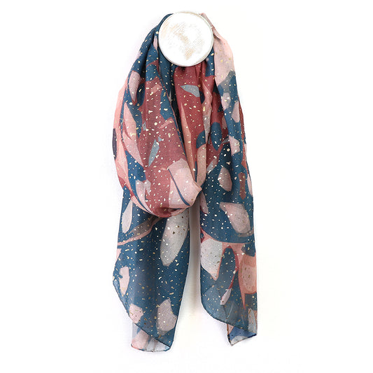 Scarf with an abstract pattern in pink and blue shades, accented with small white dots, displayed on a round hanger against a white background. This sustainable fashion scarf adds elegance while promoting eco-conscious style.