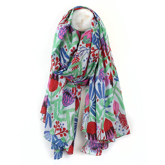 Vibrant organic cotton scarf featuring a floral and abstract leaf pattern in red, blue, and green displayed on a white mannequin head.
