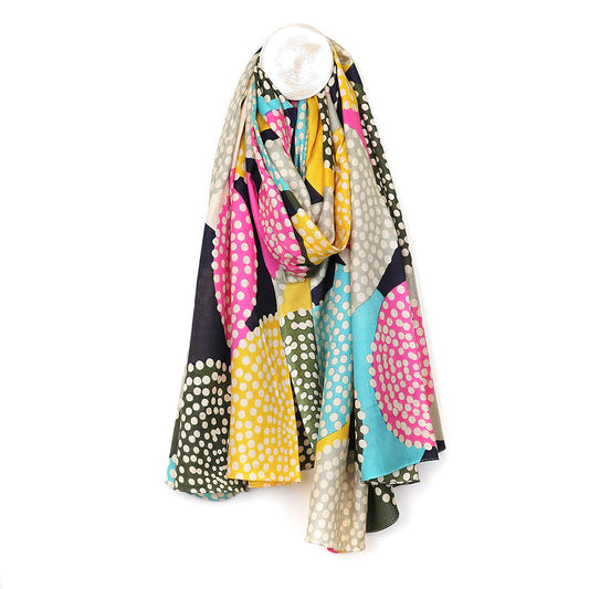 A colourful bamboo scarf draped over a hanger, displaying a dotty circle print in pink, blue, yellow, and black with white polka dots.