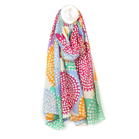 Colourful bamboo scarf with a dotty circle print in pink, orange, blue, and green hues, elegantly draped on a white hanger.