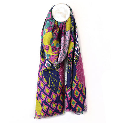 A bamboo viscose scarf, featuring a multi-print design with geometric and floral patterns, draped over a circular white hook.