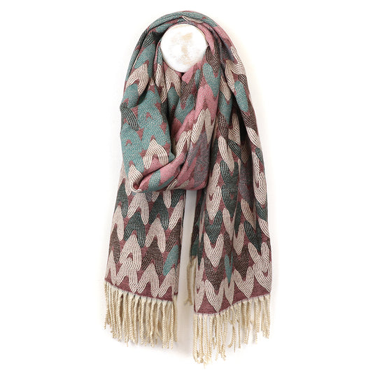 A multi-coloured jacquard design scarf with a geometric pattern in teal, pink, and beige is draped on a hanger. Beige fringe adorns the ends.