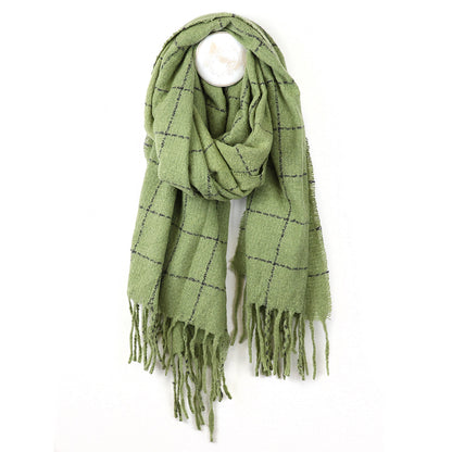 A cosy green checked scarf with a black check pattern and fringed ends, hanging from a white wall hook.
