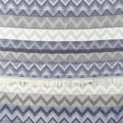 A chevron scarf woven with alternating horizontal zigzag patterns in shades of blue, grey, and white, featuring a fringe near the centre.
