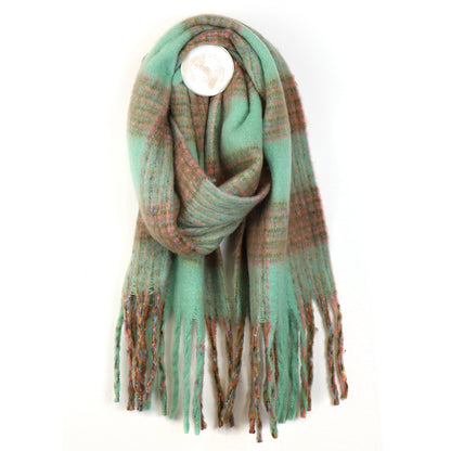 A chunky chequered scarf in green and brown tartan with fringed ends is looped against a plain white background—a perfect accessory for chilly weather.
