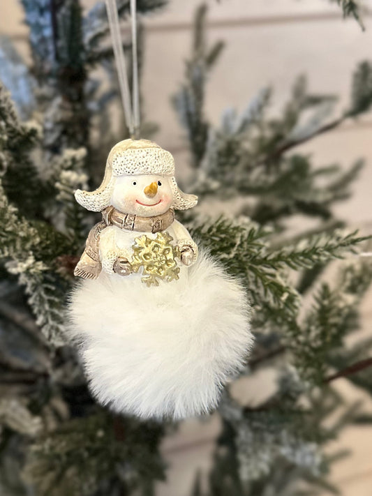 A handcrafted snowman decoration with a soft, fluffy white base hangs from a frosted Christmas tree branch, bringing charm to any festive display.
