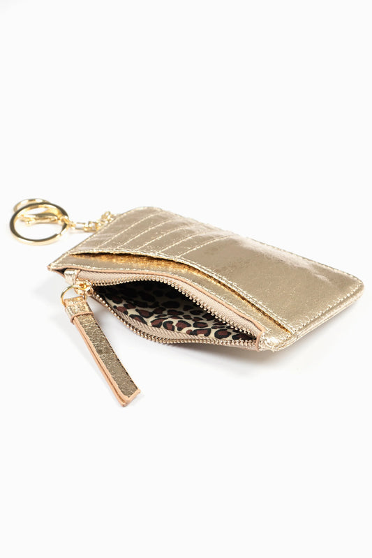 Metallic gold card holder keyring made from faux leather, featuring a zipped pocket, leopard print lining, exterior card slots, and an attached key ring, shown against a white background.