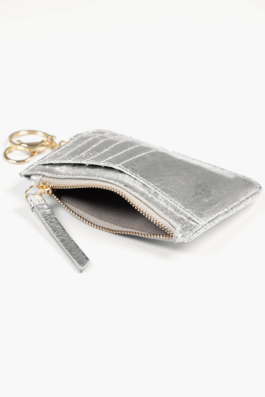 A metallic silver card holder wallet made from cracked faux leather, featuring card slots, a zip pouch, and a keyring, shown against a white background.