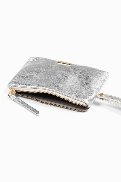 A small, metallic faux leather wristlet purse with a zip fastening and wrist strap is partially unzipped to reveal a dark interior, shown against a white background.