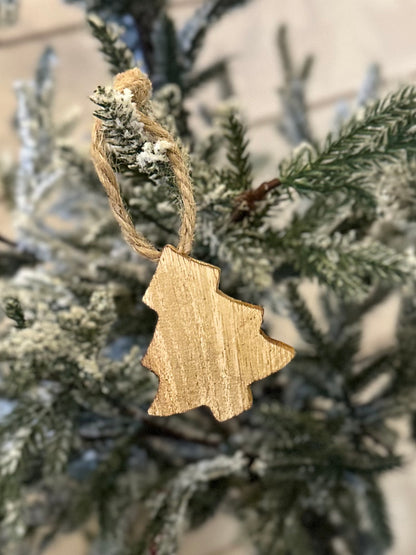 A wooden Christmas tree decoration hangs from a snow-dusted artificial pine branch, bringing a rustic touch to your festive décor.