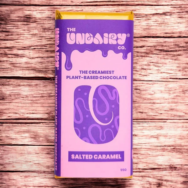 A purple and pink box of The UnDairy Co. vegan salted caramel chocolate rests on a wooden surface.