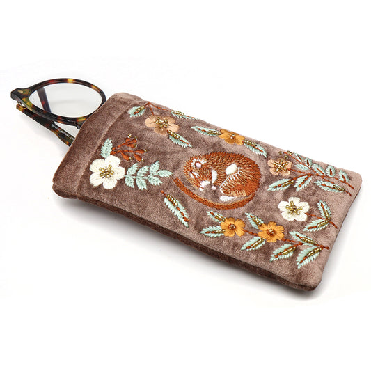 A pair of spectacles partly tucked into a taupe velvet glasses case, providing stylish protection for eyewear with embroidered flowers and a heart.