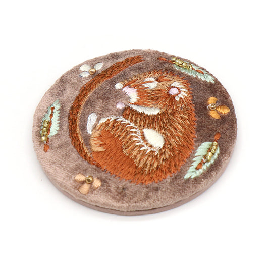 A round brown fabric patch decorates this embroidered compact mirror, displaying a curled-up mouse encircled by delicate leaves and tiny beads.
