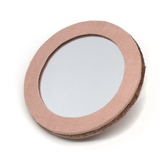 Round handheld velvet compact mirror with a pink fabric frame and brown textured backing, ideal for travel, shown against a white background.