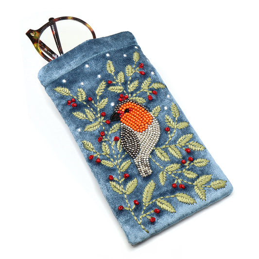 A blue velvet glasses case featuring an embroidered robin, red berries, and green leaves, with a pair of tortoiseshell spectacles partially tucked inside.