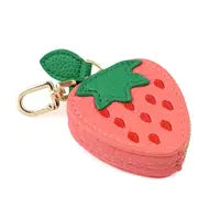 A pink and green strawberry-shaped faux leather mini purse featuring a gold clasp and keyring clip.
